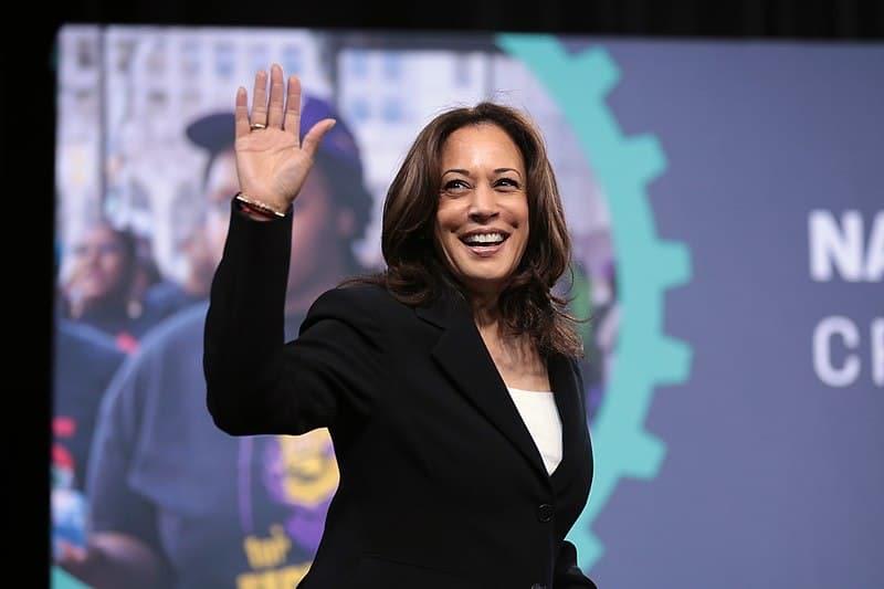 A photo of Kamala Harris smiling and waving at the camera.