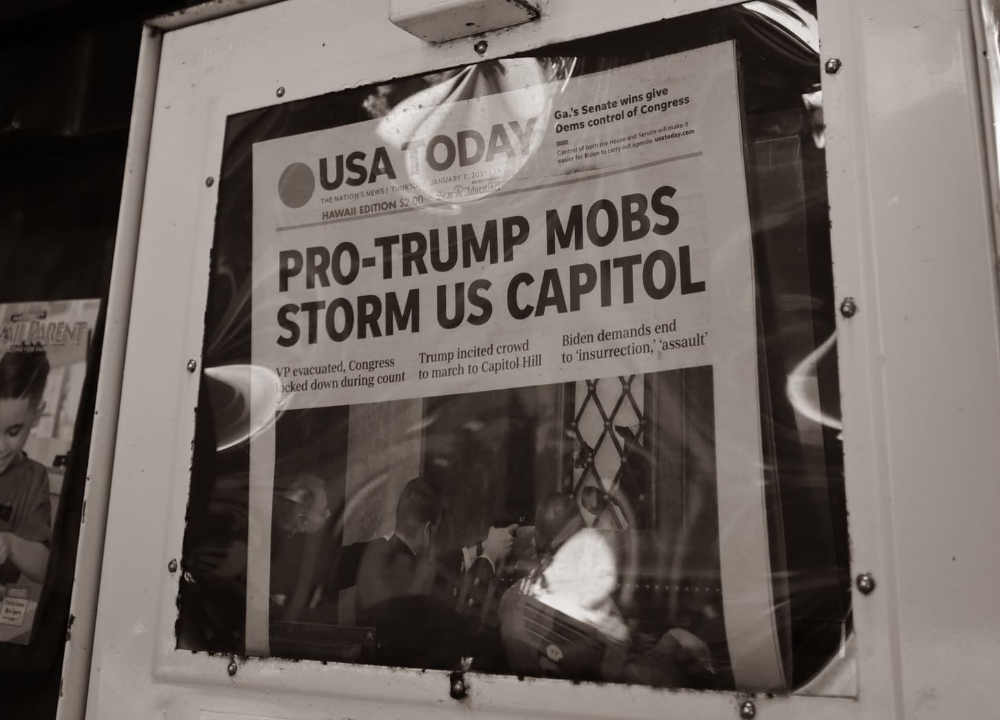 USA Today cover reads “Pro-Trump mobs storm US Capitol” in newspaper rack.