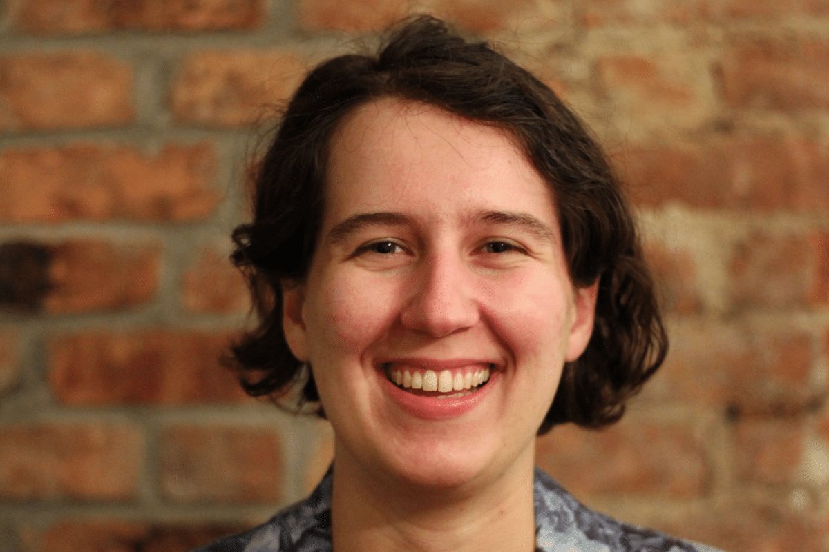 A headshot of Betsy Ladyzhets. She stands in front of a brick wall.
