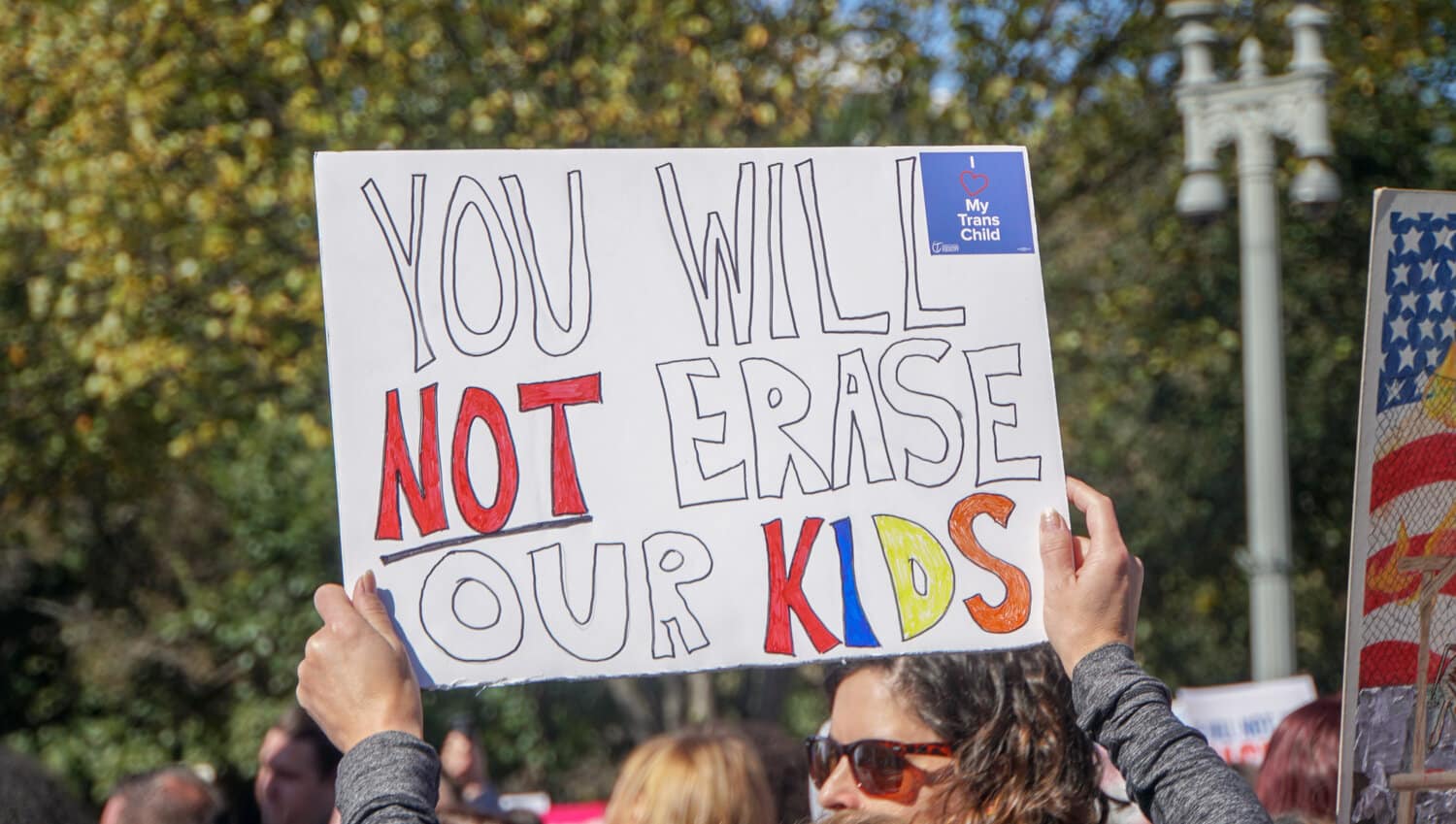 A protester marching for trans rights holds up a poster that reads You Will Not Erase Our Kids.