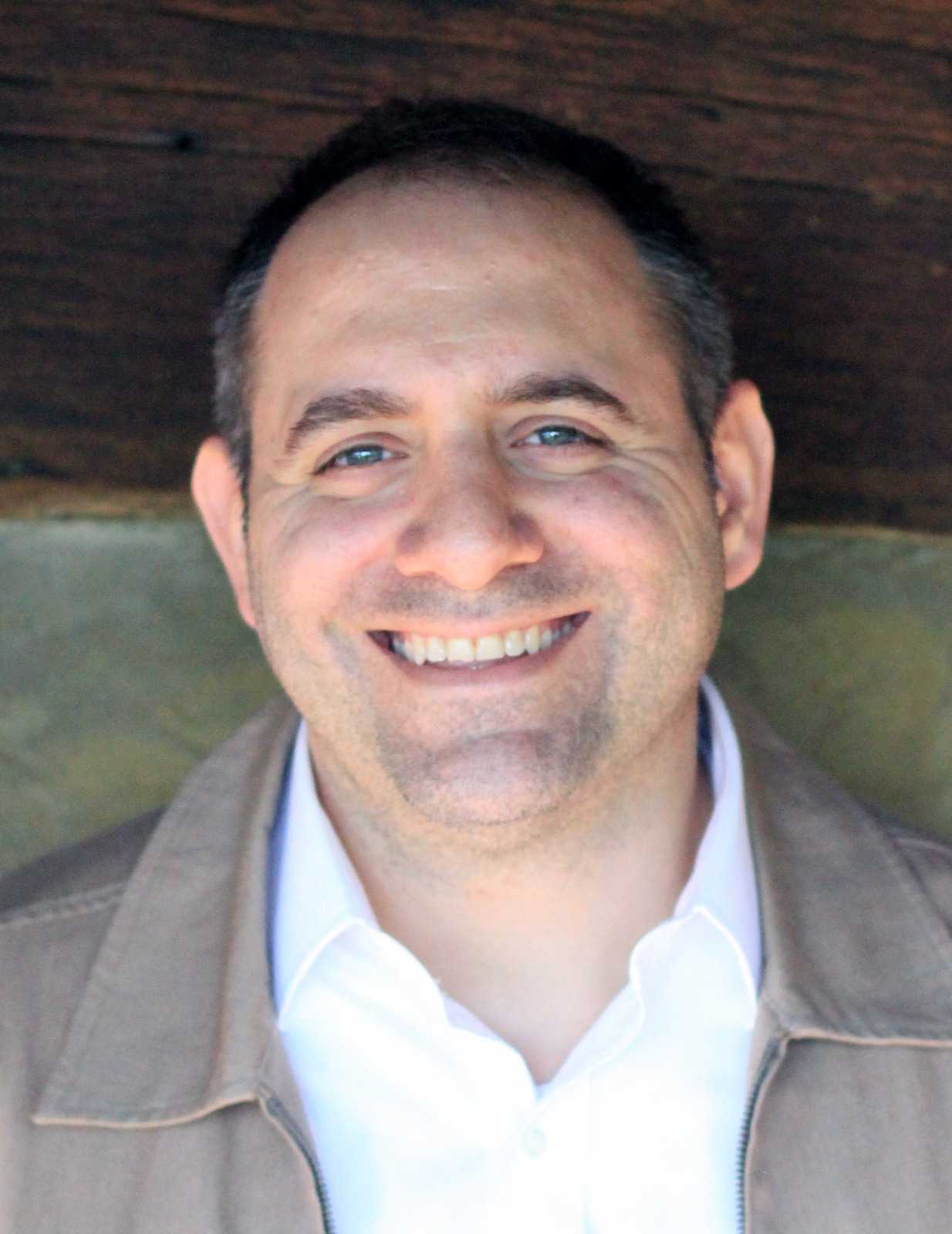 Headshot of Yousef Munayyer, a light-skinned Palestinian man smiling at the camera.