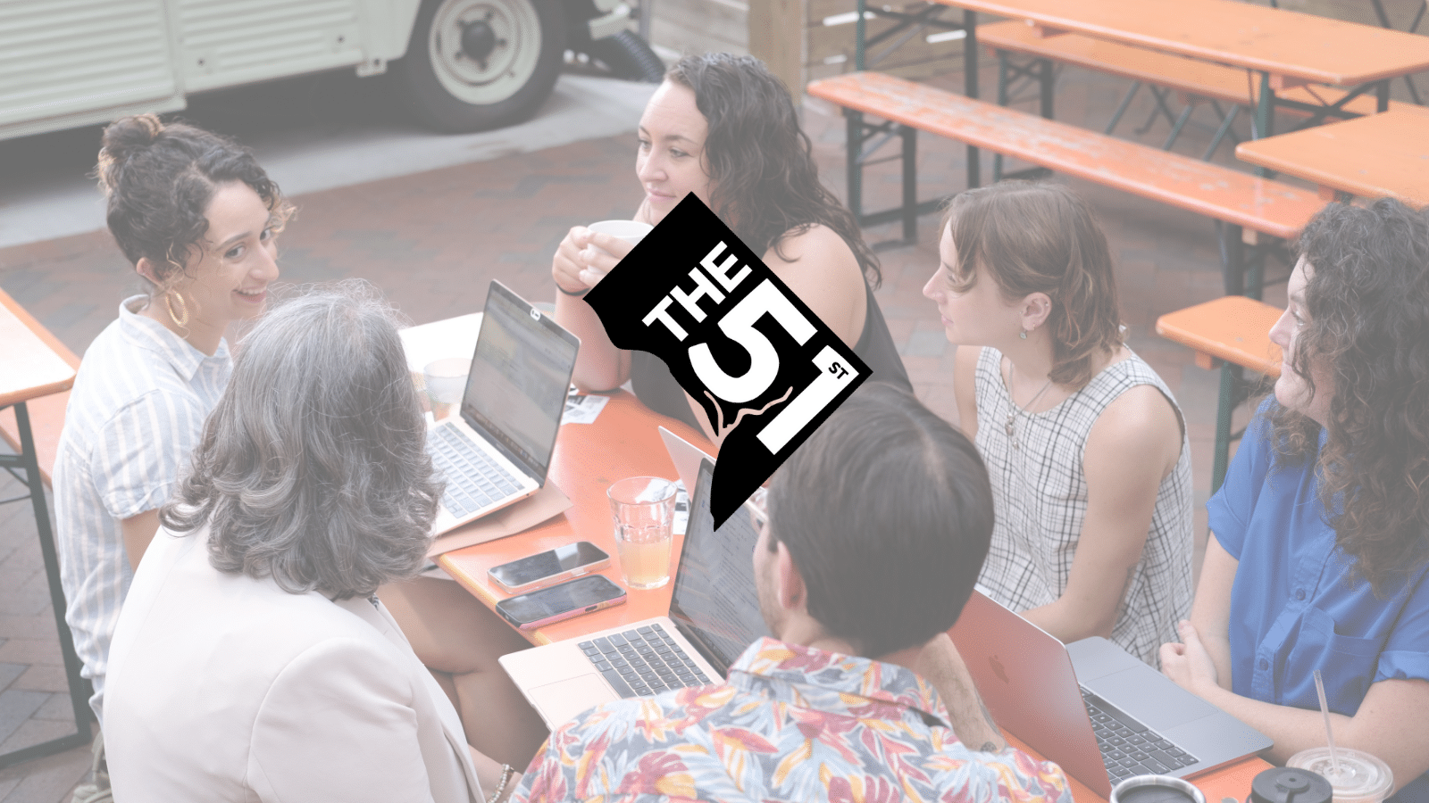 The logo of The 51st — the shape of Washington, D.C. colored black with "The 51st" laid over it, with the Potomac River running halfway between the 5 and 1 — sits on top of a slightly faded photo of the six co-founders of The 51st. They are sitting outside around a table. From top left clockwise: Natalie Delgadillo, Abigail Higgins, Colleen Grablick, Maddie Poore, Eric Falquero, and Teresa Frontado.