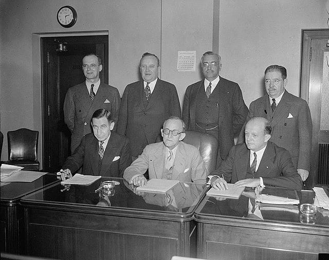 Sykes is the leftmost seated figure, and from left to right, is beside Frank R. McNinch and then-FCC chairman Paul Atlee Walker. Standing from left to right are T.A.M. Craven, Thad H. Brown, Norman S. Case, and George Henry Payne.