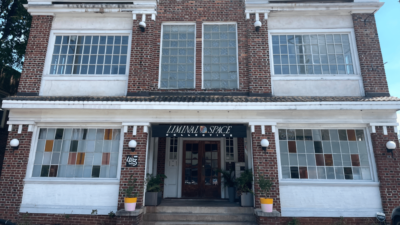 The facade of Liminal Space Collective, which is housed in a brick building with some colorful window panels.